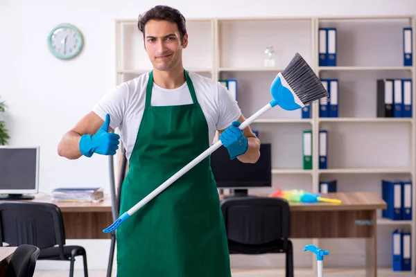 Jovem empreiteiro bonito limpando o escritório — Fotografia de Stock