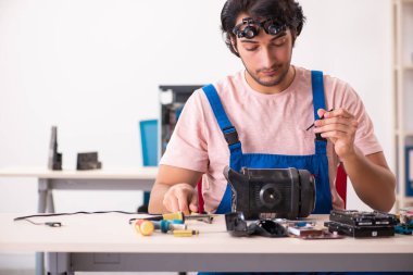Genç bir erkek müteahhit bilgisayar tamir ediyor.
