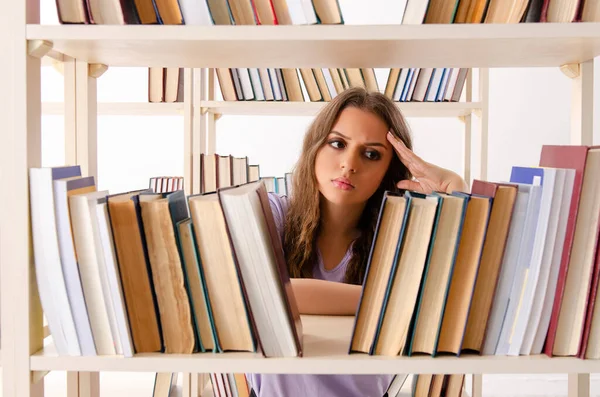 Ung kvinnlig student förbereder sig för tentamen på biblioteket — Stockfoto