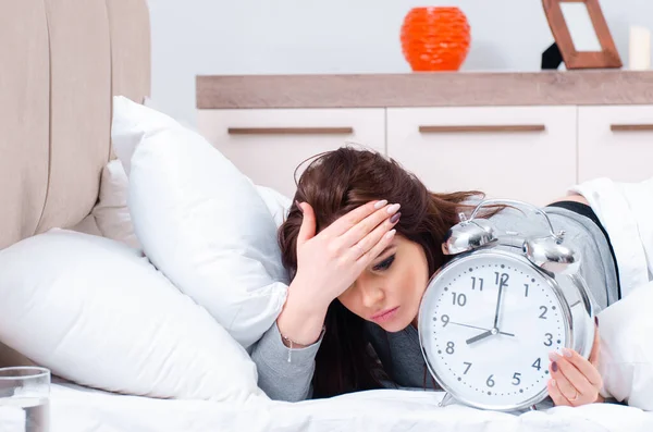 Mujer joven acostada en la cama en concepto de gestión del tiempo —  Fotos de Stock