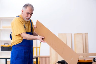 Yaşlı erkek marangoz atölyede çalışıyor.