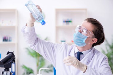 Genç erkek kimyager laboratuarda deney yapıyor.