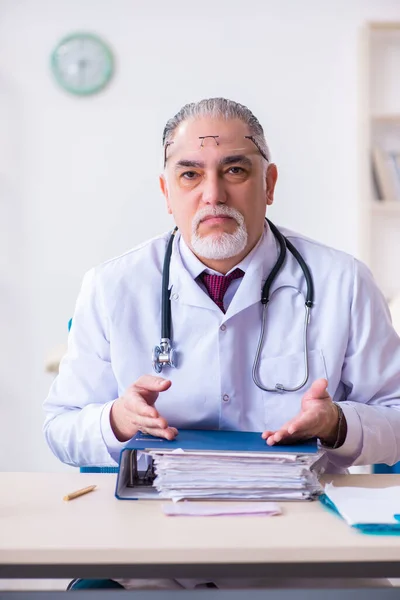 Oude mannelijke arts werkzaam in de kliniek — Stockfoto