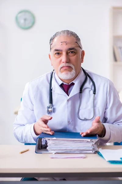 Klinikte çalışan yaşlı erkek doktor. — Stok fotoğraf