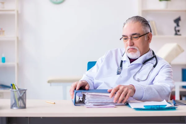 Gammal manlig läkare som arbetar på kliniken — Stockfoto