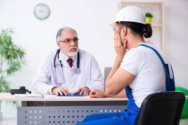 Genç erkek müteahhit yaşlı doktoru ziyaret ediyor.