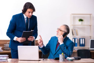 Genç ve yaşlı çalışanlar ofiste birlikte çalışıyorlar.