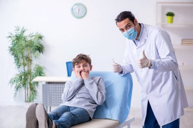 Genç çocuk hastanede doktoru ziyaret ediyor.