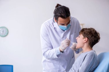 Genç çocuk hastanede doktoru ziyaret ediyor.