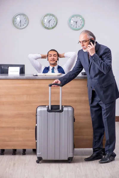 Oude zakenman bij de hotelreceptie — Stockfoto