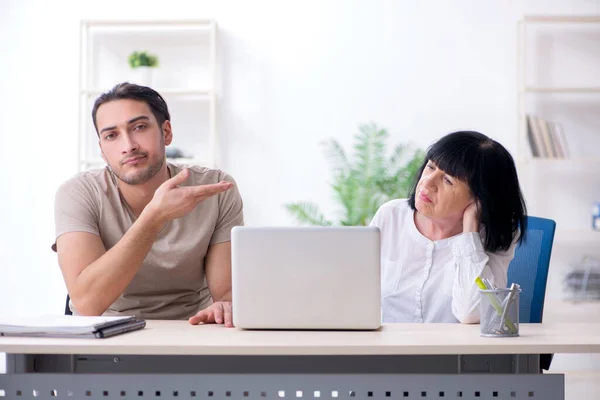 Junge männliche Mitarbeiter erklären alten Kolleginnen, wie sie zu uns kommen — Stockfoto