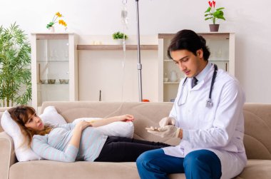 Genç, yakışıklı doktor hamile kadını ziyaret ediyor.