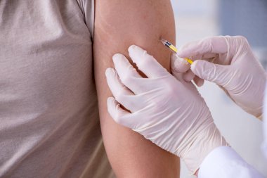 Erkek hasta aşı aşısı için doktoru ziyaret ediyor.