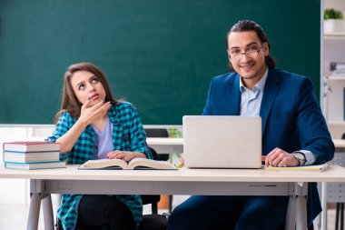 Sınıftaki genç, yakışıklı öğretmen ve bayan öğrenci.