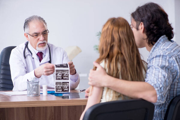 Молодая пара, посещающая пожилого врача