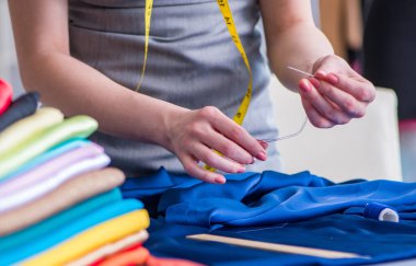 Kadın terzi dikiş dikmek için dikiş dikiyor.