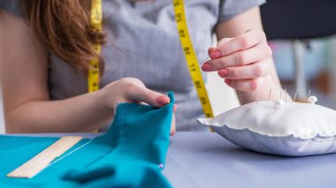 Kadın terzi dikiş dikmek için dikiş dikiyor.