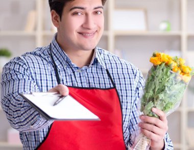 Çiçekçi asistanı bir demet çiçek veriyor.