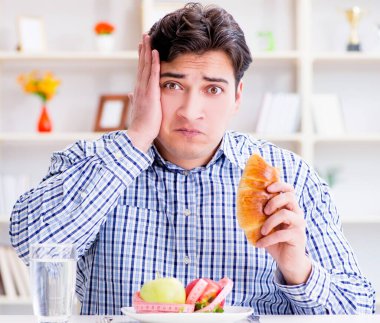 Diyet dolandırıcılığında sağlıklı yemek ve ekmek arasında ikilem yaşayan bir adam.