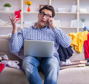 Genç adam dağınık bir odada çalışıyor.