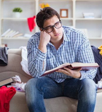 Genç adam dağınık bir odada çalışıyor.