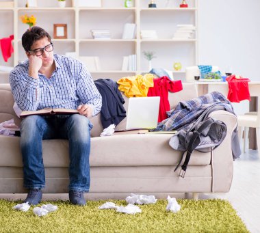 Genç adam dağınık bir odada çalışıyor.