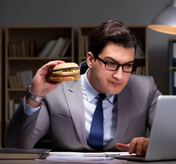 ビジネスマンは夜遅くハンバーガーを食べて — ストック写真