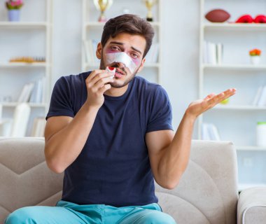 Genç adam estetik cerrahi burnundan sonra evde iyileşiyor.