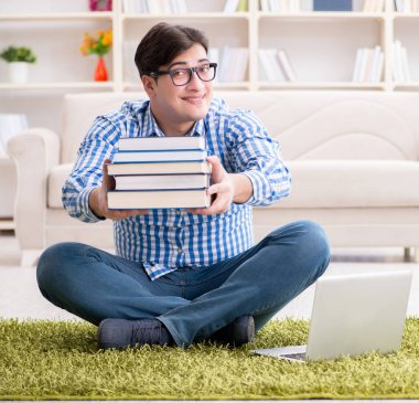 Genç yakışıklı adam evde yerde oturuyor.