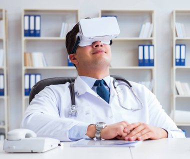 Sanal gerçeklik kulaklığı olan genç doktor ofiste çalışıyor.