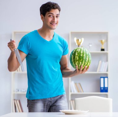 Evde karpuz yiyen bir adam.