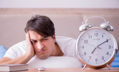 Yataktaki adam alarm yüzünden uykusuzluk çekiyor.