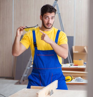 Genç tamirci marangoz odun kesiyor.