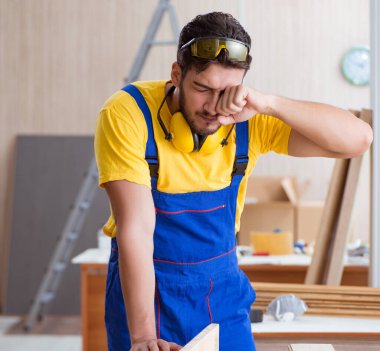 Genç bir marangoz dairesel testereyle odun kesiyor.