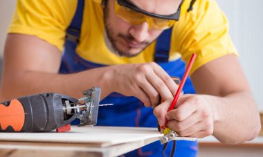 Genç bir marangoz dairesel testereyle odun kesiyor.