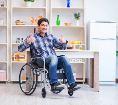 Engelli genç koca mutfakta çalışıyor.