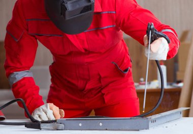 Kaynak tabancası elektrot ve kask takan genç bir tamirci.