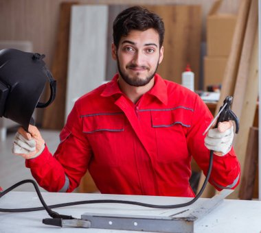 Kaynak tabancası elektrot ve kask takan genç bir tamirci.