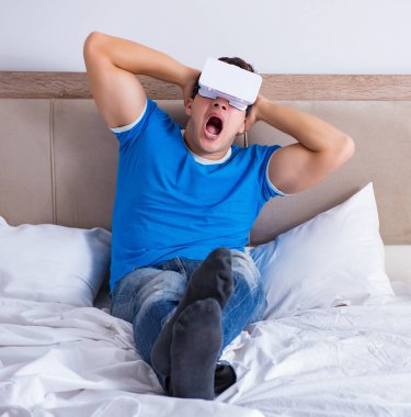 Yatakta sanal gerçeklik başlığı takan genç bir adam.