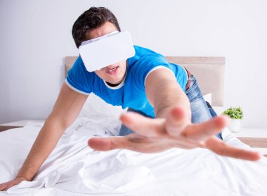 Yatakta sanal gerçeklik başlığı takan genç bir adam.