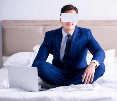 Yatak odasında sanal gerçeklik kulaklığı takan bir iş adamı.