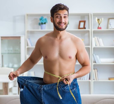 Kilo verme konseptinde büyük beden pantolon giyen bir adam.
