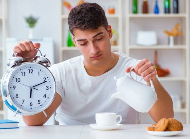 Çalar saati olan bir adam kahvaltıda uyuyakalıyor.