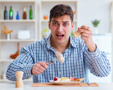 Yemek için evde tatsız yemekler yiyen bir adam.