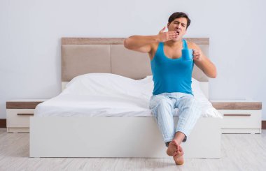 Genç adam yatakta uyanıyor.