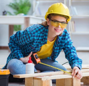 Tamirci kadın marangoz ahşap döşemeleri kesiyor.