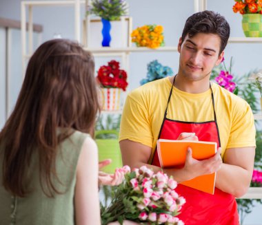 Çiçekçi dükkanında çiçek satıyor.