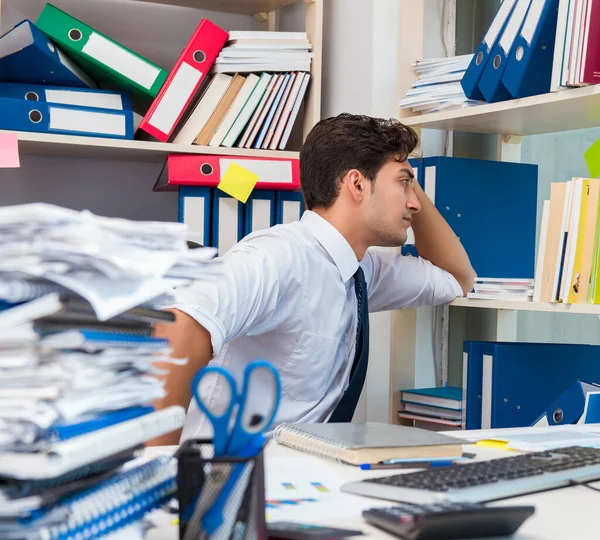 Affärsman som arbetar på kontoret med högar av böcker och papper — Stockfoto