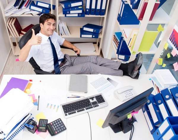 Biznesmen pracujący w biurze z stosami książek i dokumentów — Zdjęcie stockowe