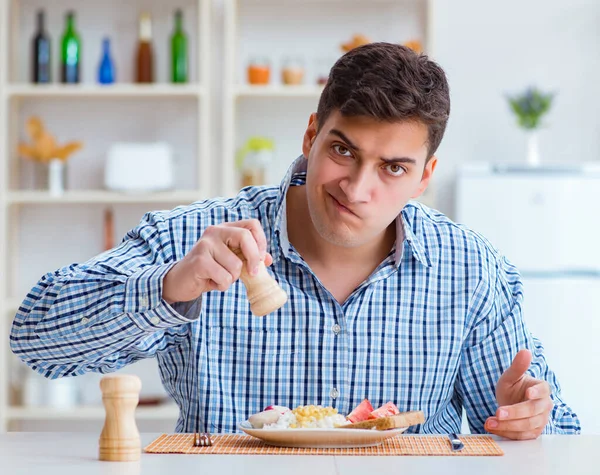 Jovem marido comendo comida insípida em casa para o almoço — Fotografia de Stock